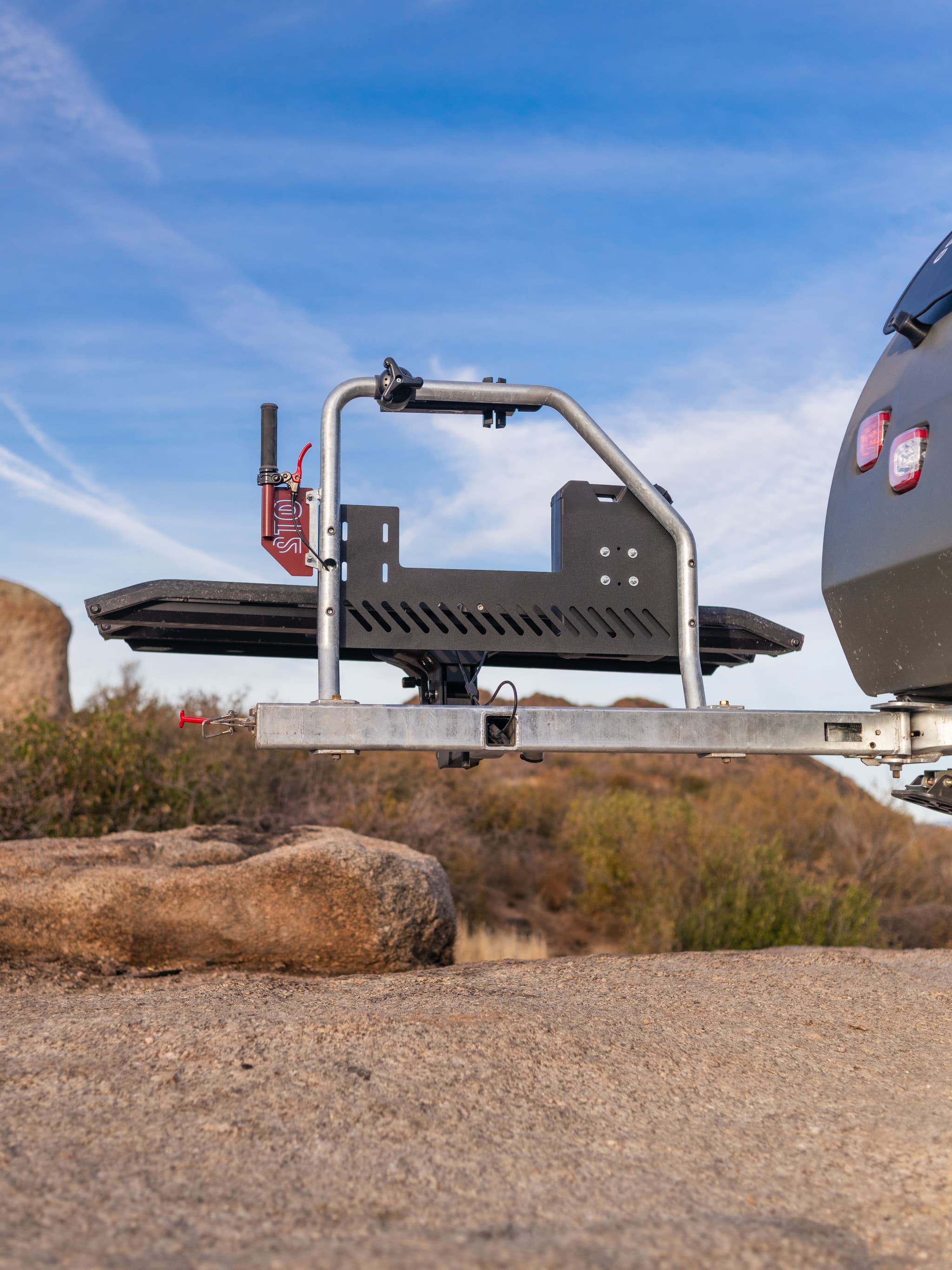 Close-up of the TOPO2 MTB’s integrated rear utility rack system, empty and ready for gear, with desert rocks and blue sky behind it.